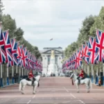 Avenida de The Mall en Londres con el palacio de Buckingham al fondo y todo lleno de banderas de Reino Unido a lo largo de la avenida - Merece la pena el London Pass cuando visitas londres?