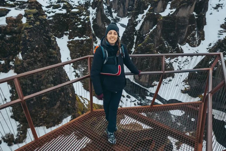 Cañon2 Chica posando a la cámara en una plataforma de hierro en lo alto de un cañón en Islandia. El paisaje esta todo nevado